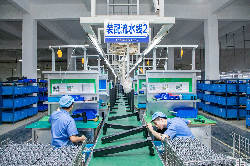 The workers are assembling the sit and stand desk frame parts on the assembly line