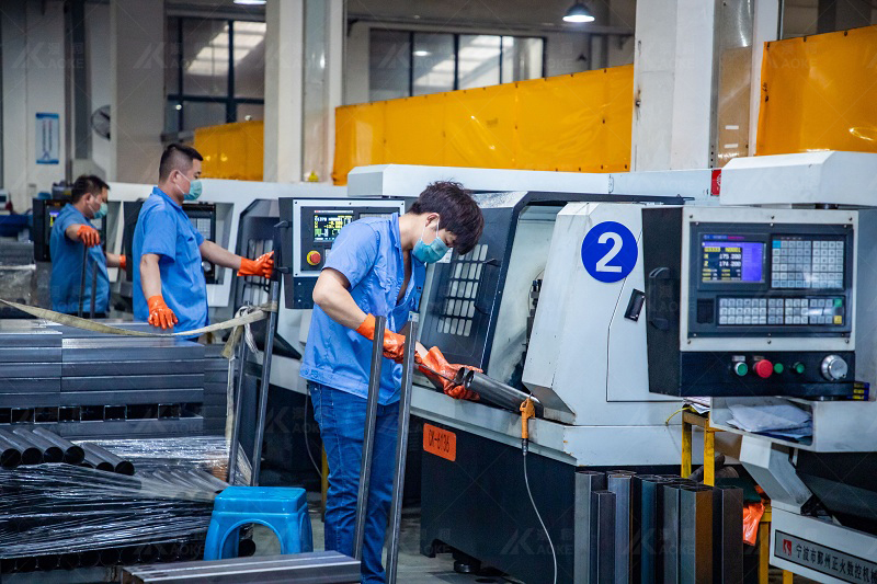 Workers are removing burrs from the edge of a sitting stand desk leg