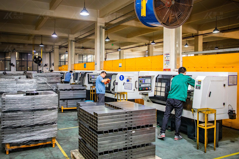 Workers in further processing standing desk frame parts